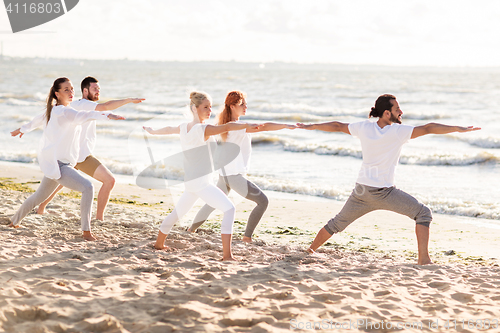 Image of people making yoga in warrior pose on beach