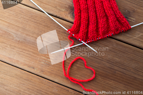Image of knitting needles and thread in heart shape on wood