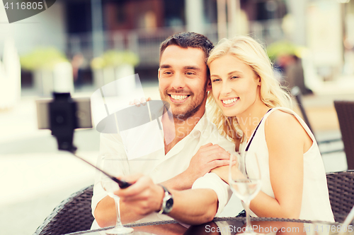 Image of happy couple taking selfie with smartphone at cafe