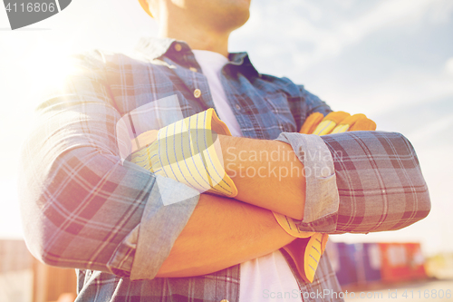 Image of close up of builder crossed hands in gloves