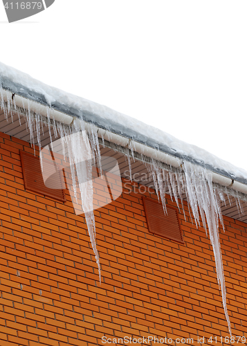 Image of Snow-covered roof with icicles on white background