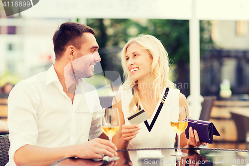 Image of happy couple with bank card and bill at restaurant