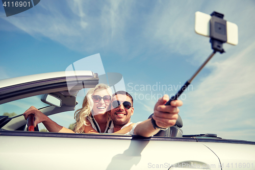 Image of happy couple in car taking selfie with smartphone