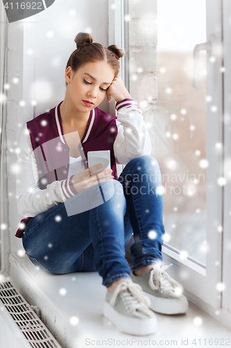 Image of sad pretty teenage girl with smartphone texting