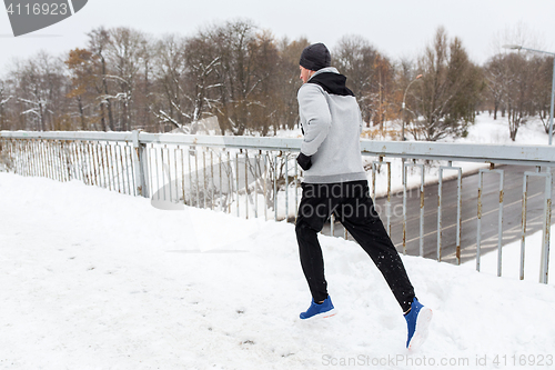 Image of man in earphones running along winter bridge