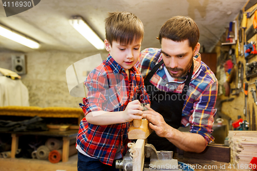 Image of father and son with plane shaving wood at workshop