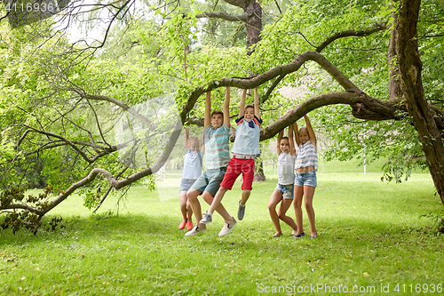 Image of happy kids hanging on tree in summer park