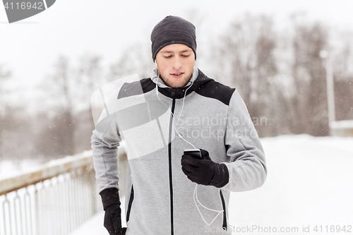 Image of happy man with earphones and smartphone in winter