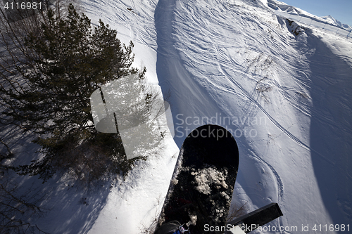 Image of Snowboard over off-piste slope in sun winter day