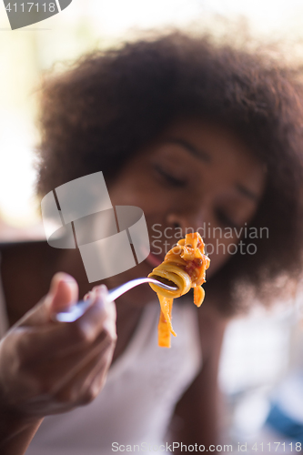 Image of a young African American woman eating pasta