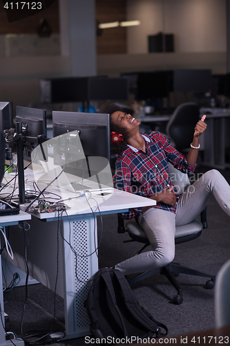 Image of woman at her workplace in startup business office listening musi