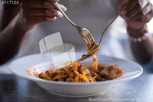 Image of a young African American woman eating pasta