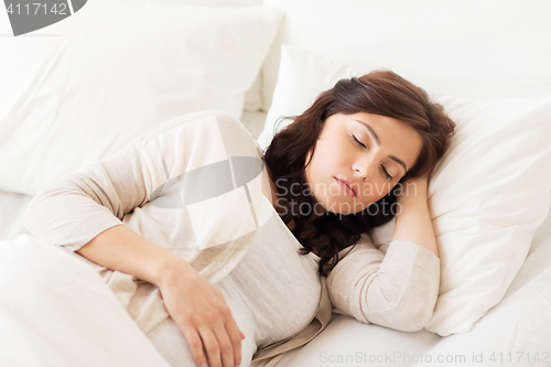 Image of happy pregnant woman sleeping in bed at home