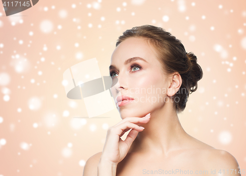 Image of beautiful young woman touching her face over snow