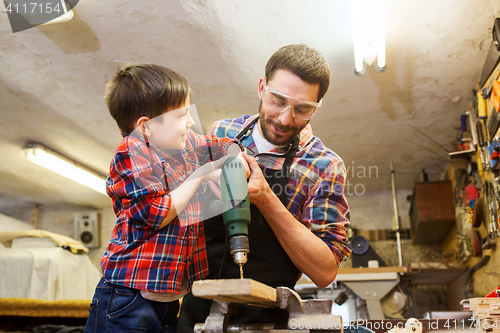 Image of father and son with drill working at workshop