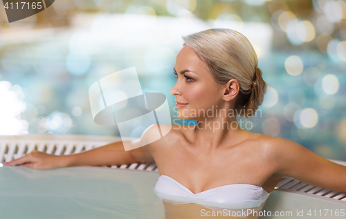 Image of happy woman sitting in jacuzzi at poolside