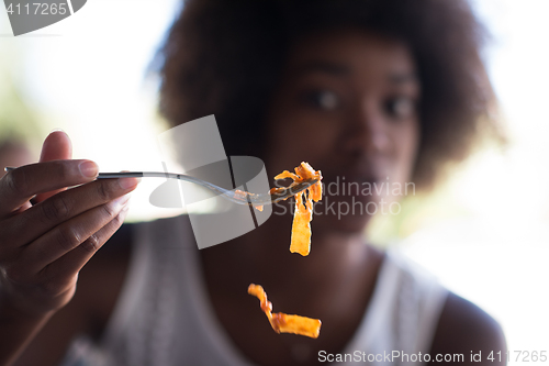 Image of a young African American woman eating pasta
