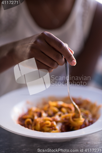 Image of a young African American woman eating pasta