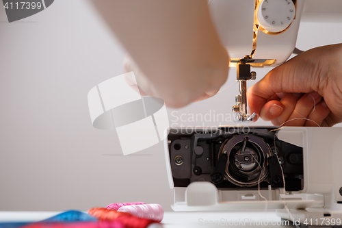 Image of Girl prepares sewing-machine to work