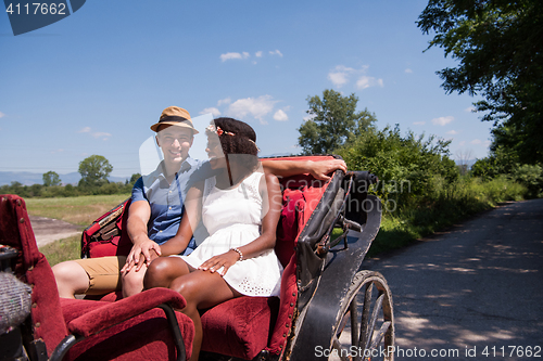 Image of multiethnic couple sitting in a horse carriage