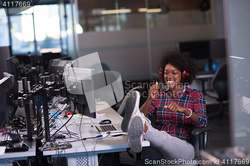 Image of woman at her workplace in startup business office listening musi