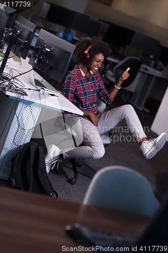 Image of woman at her workplace in startup business office listening musi