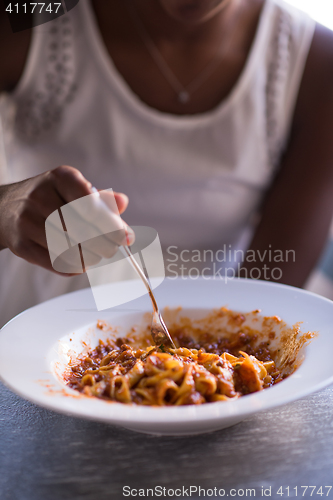 Image of a young African American woman eating pasta