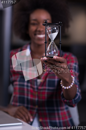 Image of young woman at office looking at sand  clock