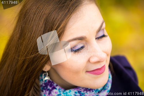 Image of Rub a beautiful girl with closed eyes on a blurred background of autumn leaves