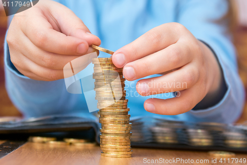 Image of Child amassed a large pile of gold coins, close-up