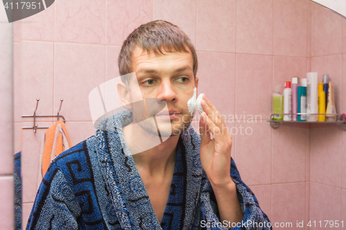 Image of The young man begins to apply shaving foam on face
