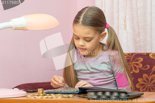 Image of The child looks at a coin album for collectibles