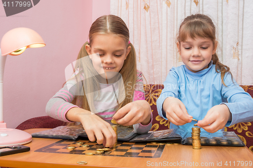 Image of Two children build towers of coins