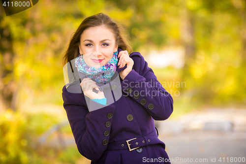 Image of Girl in a dark blue coat against the background of autumn leaves
