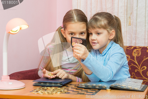 Image of Two children looking at a coin through a magnifying glass