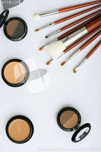 Image of makeup brush and cosmetics, on a white background