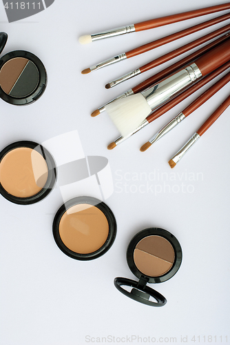 Image of makeup brush and cosmetics, on a white background