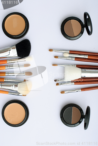 Image of makeup brush and cosmetics, on a white background