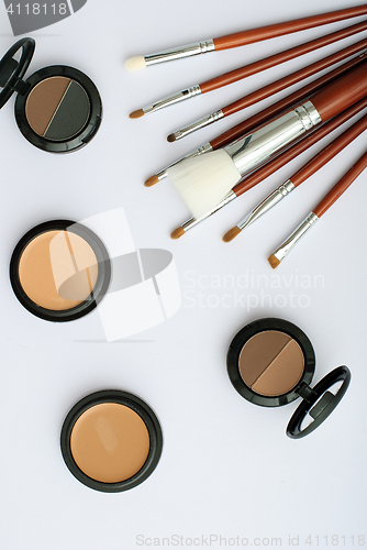 Image of makeup brush and cosmetics, on a white background