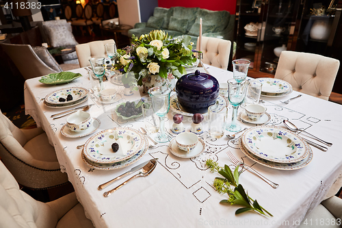 Image of Beautifully decorated table set with flowers, candles, plates and serviettes for wedding or another event in the restaurant.