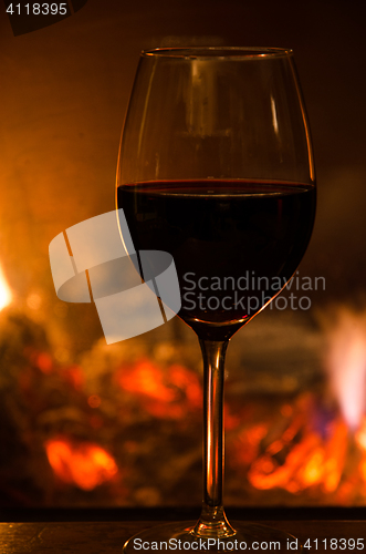 Image of Glass of red wine in front of a fireplace