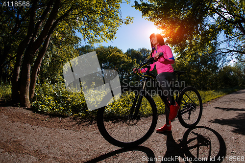 Image of Young woman having fun riding a bicycle in the park.