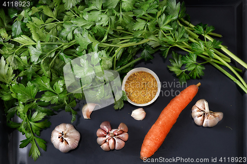 Image of Parsley leaves and vegetables on a dark tray.