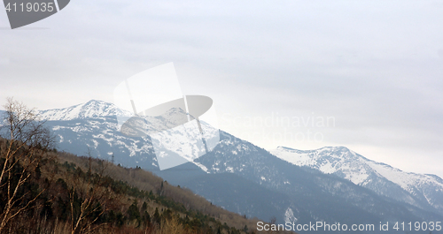 Image of Mountain ridges covered with snow and overcast sky.