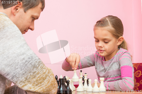 Image of Girl makes the next move while playing chess with the coach