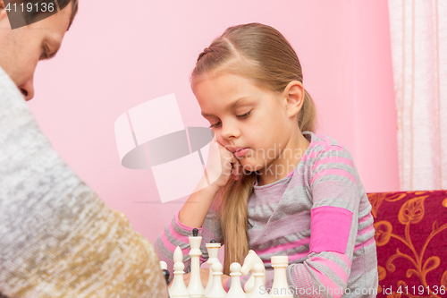 Image of Seven-year daughter is thinking about the next move, playing chess