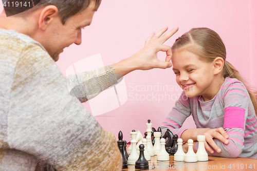 Image of Dad won a game of chess at a daughter on a bet and hit her on the head