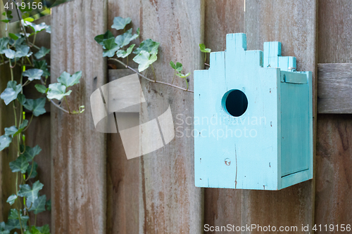 Image of Blue birdhouse on a wooden fence