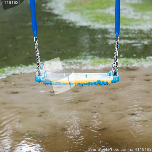 Image of Plastic swing hanging over a puddle