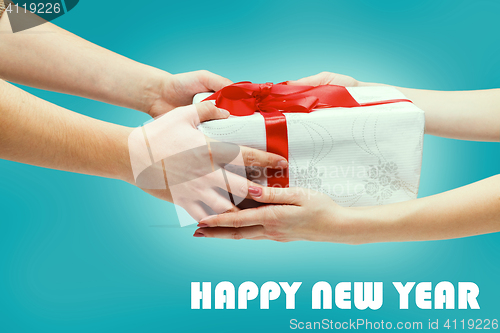 Image of Female and male hands holding gift on blue background